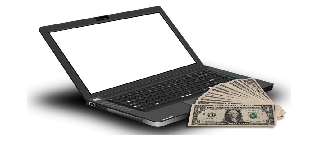 dollar bills in front of a laptop