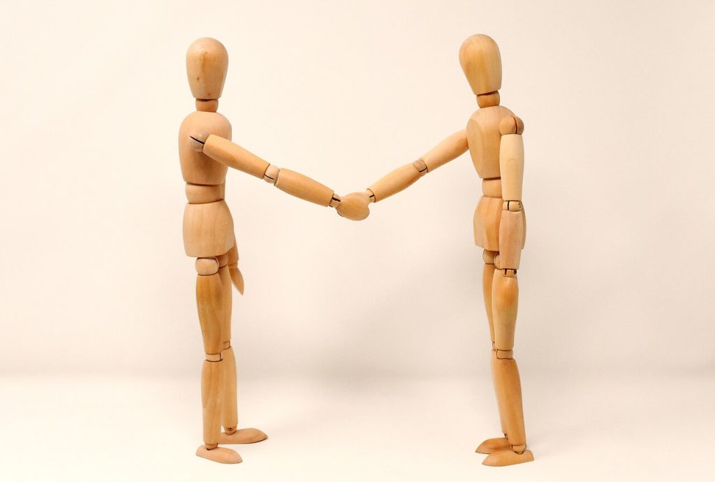 two wooden dolls shaking hands